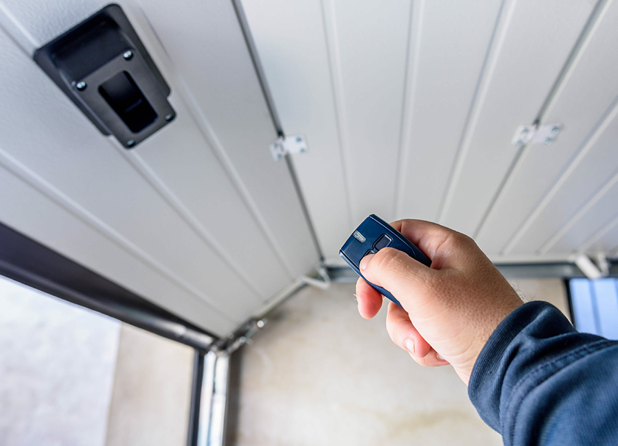 Un technicien teste le fonctionnement après avoir poser cette porte de garage sectionnelle verticale